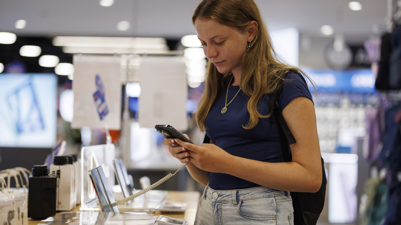 Girl testing a demo smartphone in an electronics store.