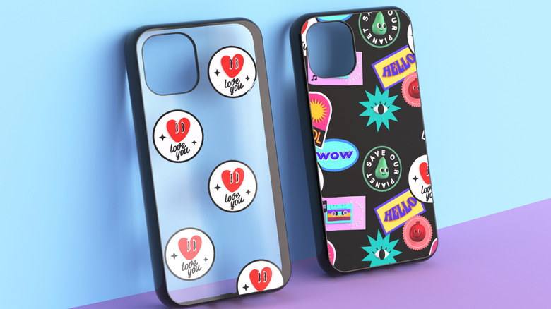 Two stylish phone cases leaning up against a wall with stickers on them.
