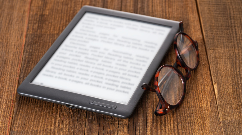Close-up of e-reader with eyeglasses beside it