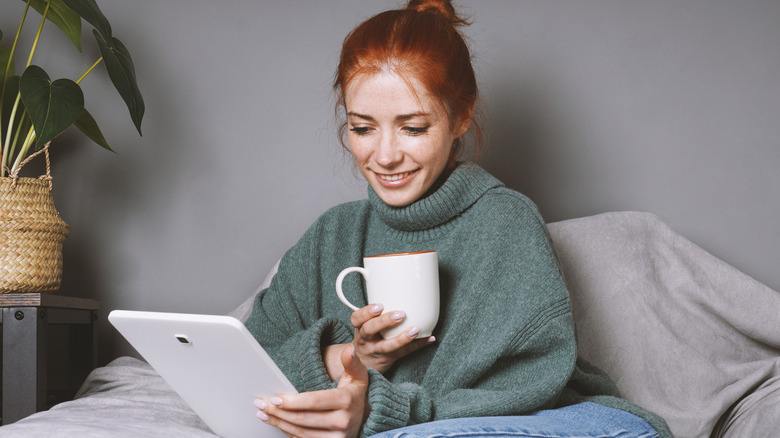 A woman in bed reading on a tablet.