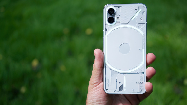 Someone holding up the original Nothing Phone 1 outdoors.