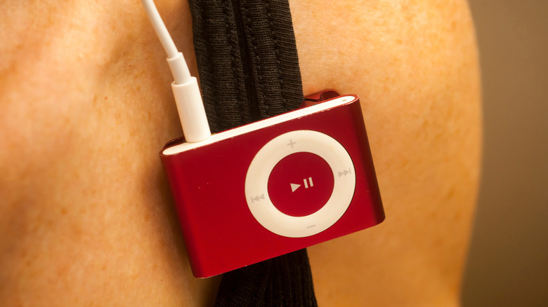 Red iPod Shuffle clipped to shirt strap with wired earbuds connected