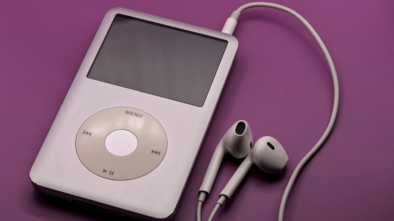 Classic iPod with wired earbuds resting on purple background