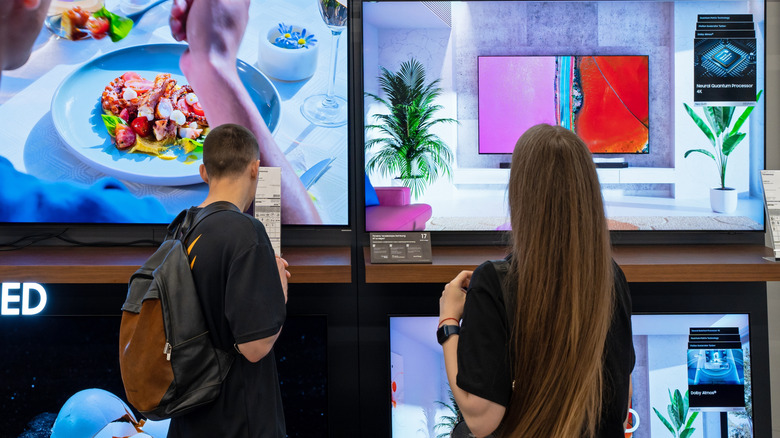 Back view of two people browsing OLED TVs
