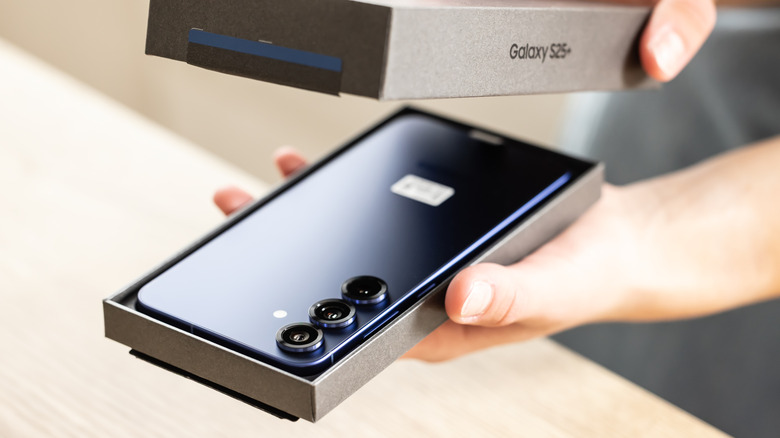 Samsung Galaxy S25 phone being unboxed with its rear cameras facing upward.