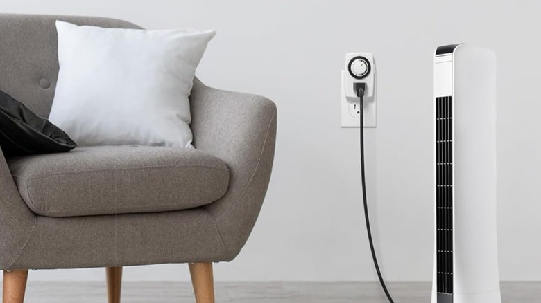 A tower fan in a living room plugged into a BN-Link outlet timer.