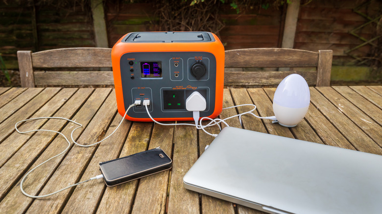 A large portable solar-powered battery pack charges devices on a table