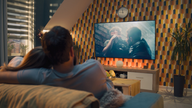 a couple watches an action movie or show on their home theater system