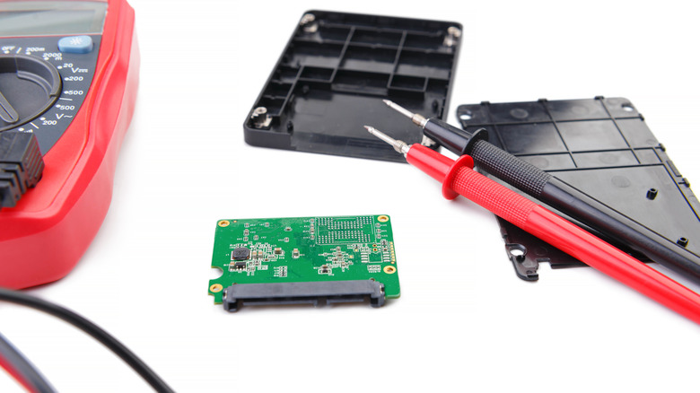 A disassembled SSD with a voltmeter next to it