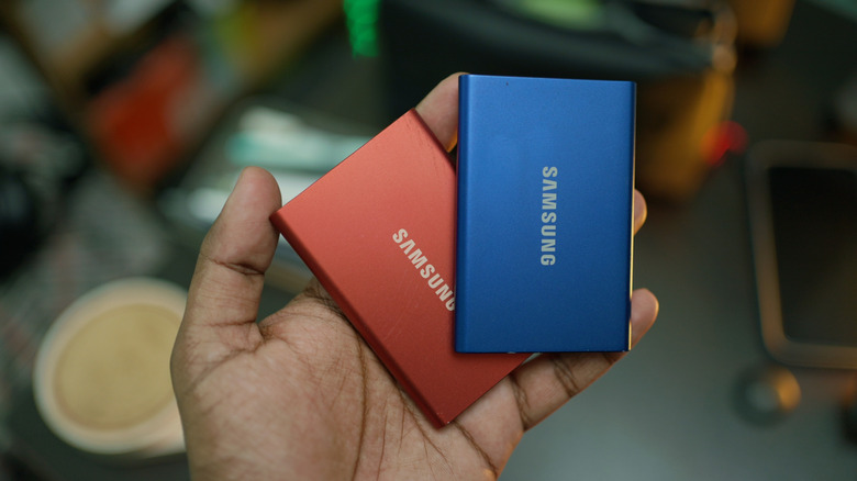 A person holding two SSDs in their hand