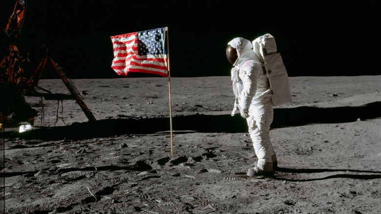 Buzz Aldrin facing American flag planted on the moon