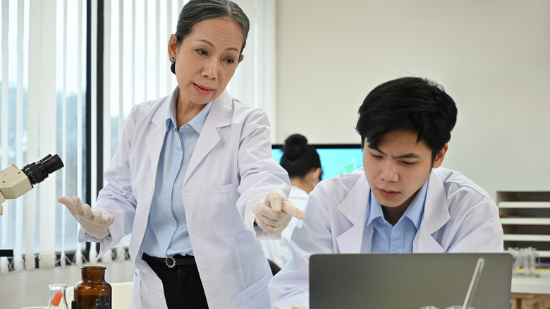 scientists discussing their findings, looking at a laptop