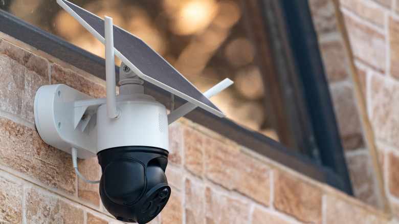 a solar powered home security camera on a brick wall