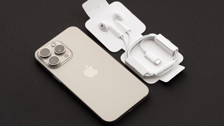 An iPhone sitting on a table next to a pair of USB-C Apple Earpods in their packaging