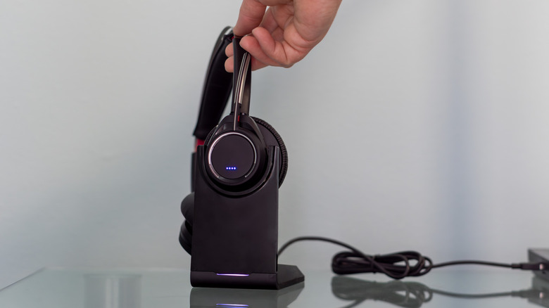 Someone reaching for a USB headset resting in a dock