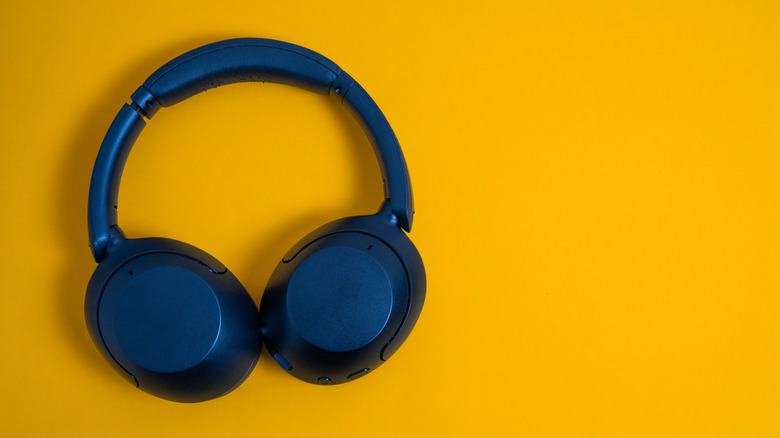 Blue headphones sitting flat on a yellow surface