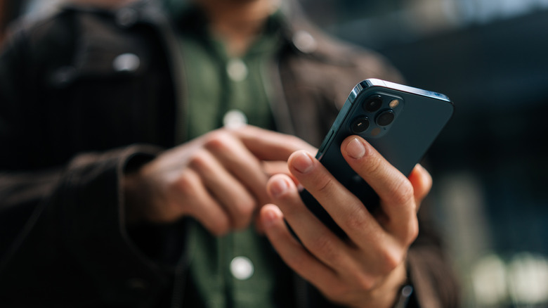 A closeup of a man's hands holding a blue iPhone