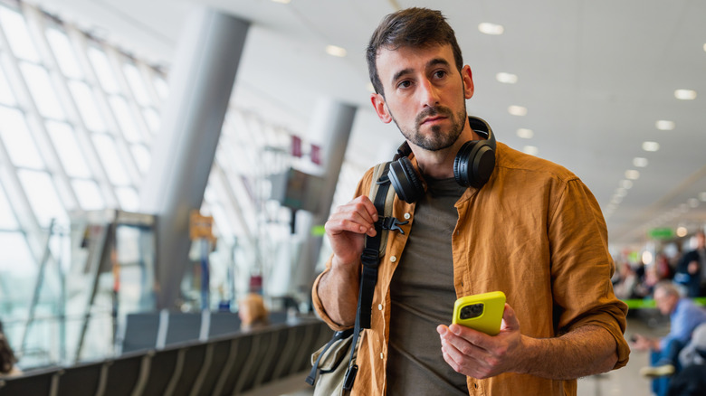 Man wearing headphones around his neck at the airport.