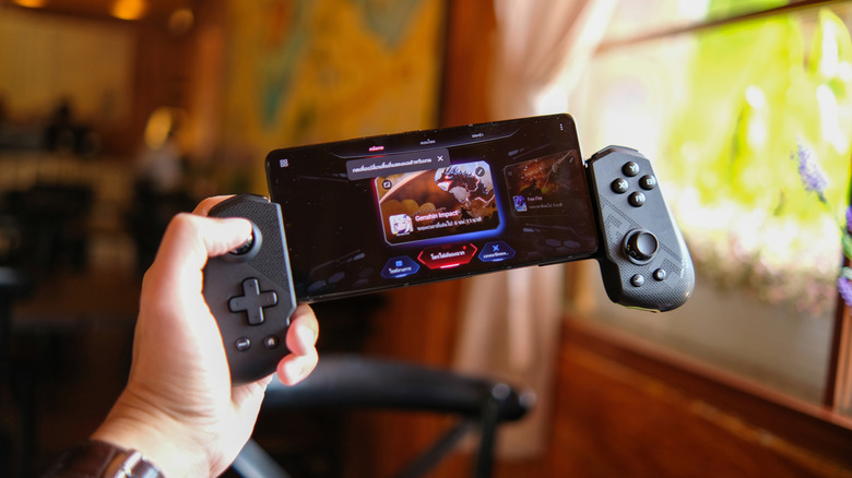 A hand holding an Asus ROG phone with controllers on either side
