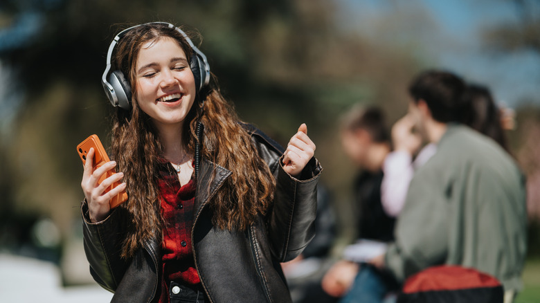 A student enjoying music from her phone using wireless headphones.