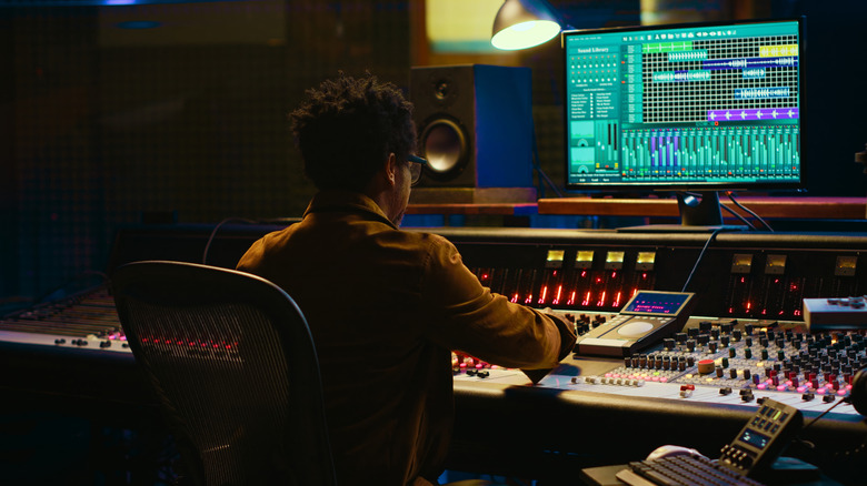 An audio producer at a mixer board who is able to adjust levels and compression.
