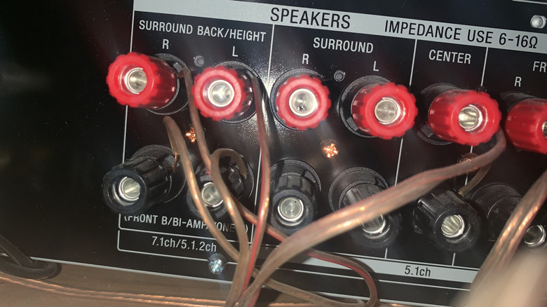 The back panel of a surround sound receiver showing speaker cables routing to multiple locations