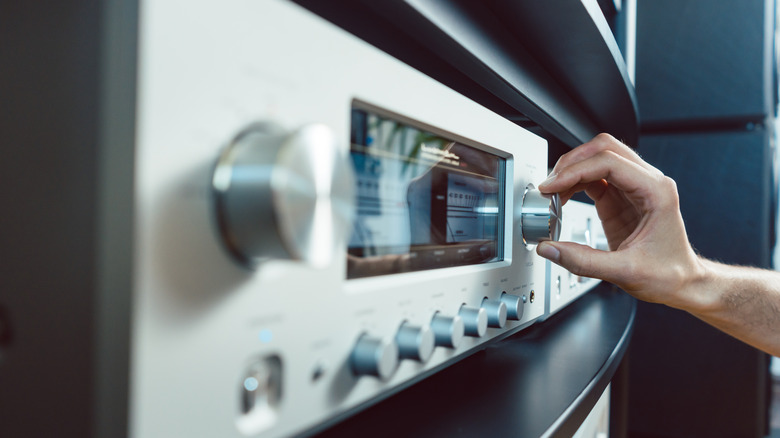 A person adjusting the volume on a receiver