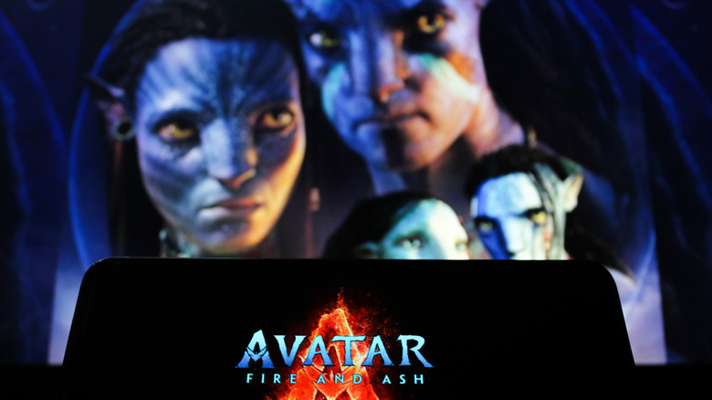 The "Avatar: Fire and Ash" logo on a smartphone display, with the film's characters in the background