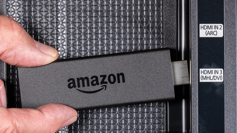 A person connects an Amazon Fire TV Stick to a TV.