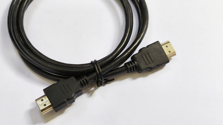 A black HDMI cable coiled up and tied with a black twist tie on a white background.