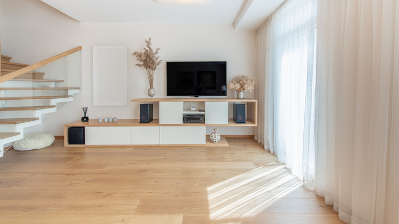 A television set up in a bright room featuring sheer curtains with light coming through them.