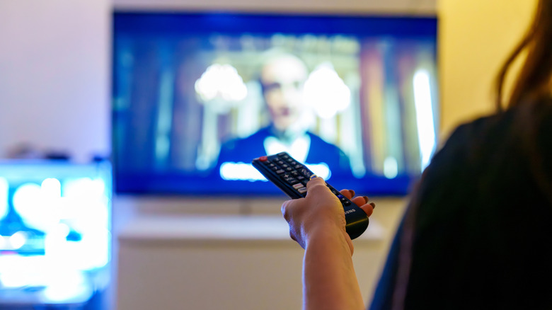 A person watching something on a TV while holding a remote.
