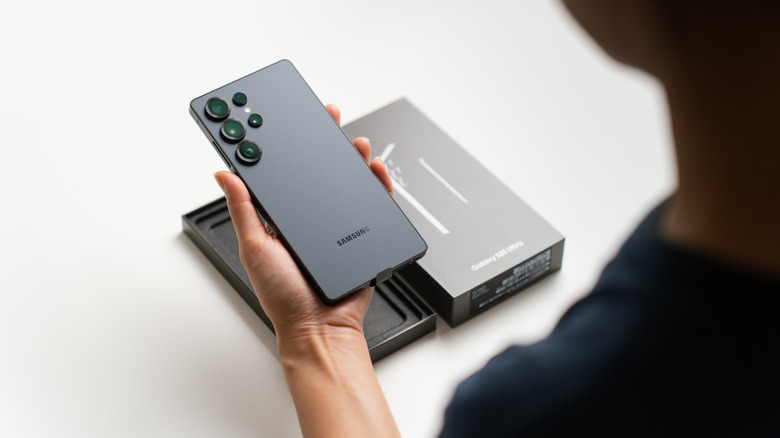 person holding a new Samsung Galaxy S25 ultra with its box kept in the background
