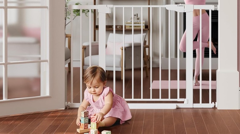 The Cumbor S7V2 baby gate, with a baby on one side and an adult on the other side.