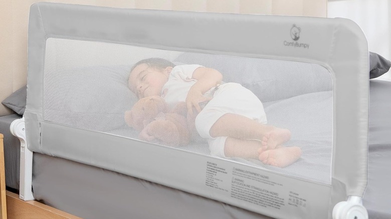 The ComfyBumpy Extra Tall bed rail installed on a bed, with a child sleeping on it.