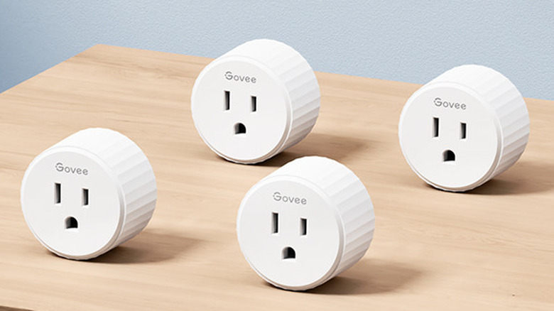 Four Govee H5083 smart plugs on a wooden surface.