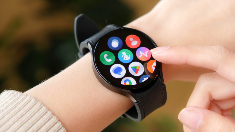 Close up of a Samsung Galaxy smartwatch on a wrist, a finger touching the screen.