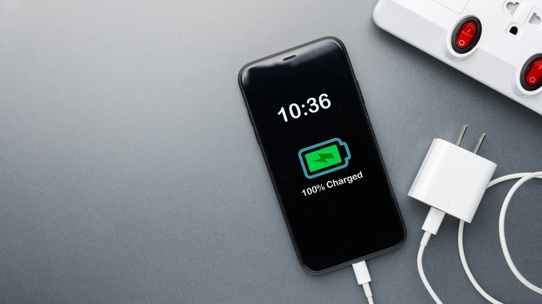 Smartphone showing 100% charged graphic next to a USB block and outlet
