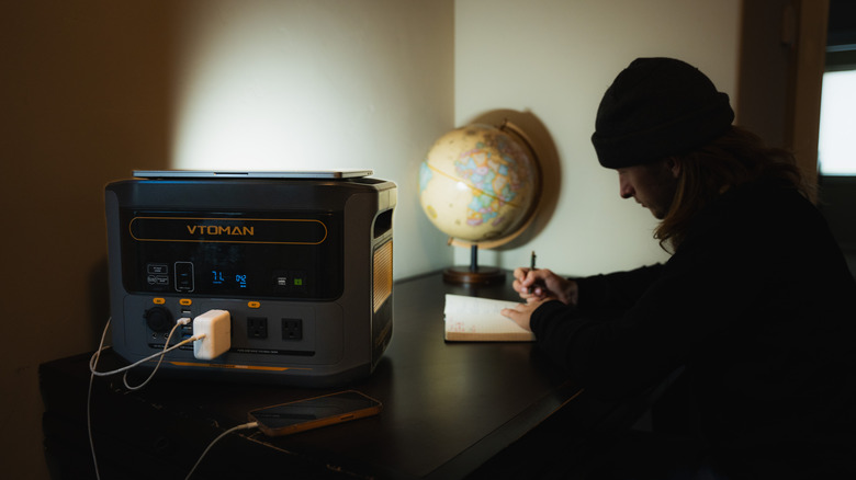 VTOMAN Power Station sitting on a table charging a phone next to a person