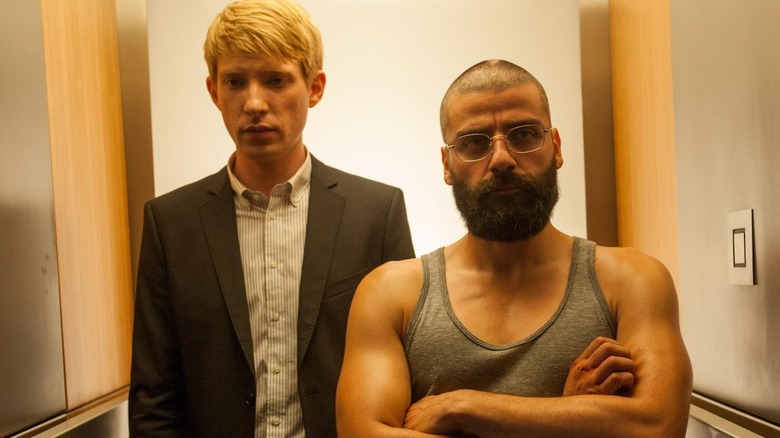 Domhnall Gleeson as Caleb stood behind Oscar Isaac as Nathan Bateman in Ex Machina