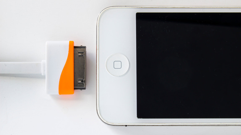 A 30-pin charging cable being connected to an iPhone 4s