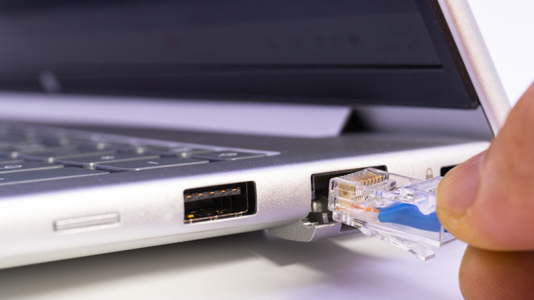 Somebody plugging an Ethernet cable into a laptop.