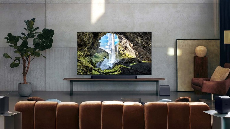 The Samsung HW-990F soundbar system set up in a modern living room with gray cement walls.
