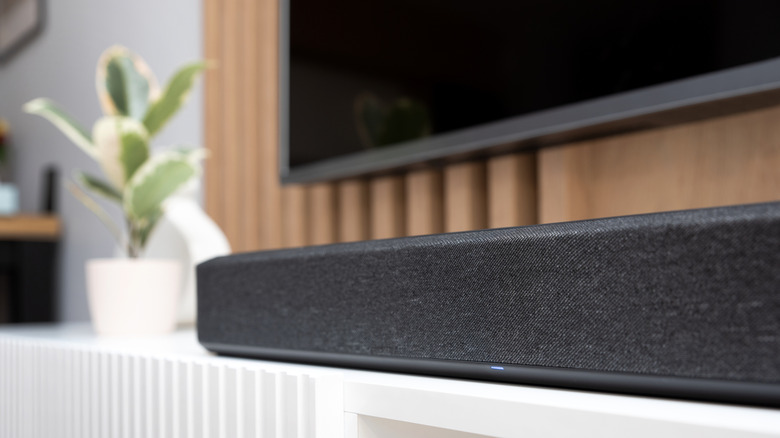 A dark gray soundbar placed below a wall-mounted TV.