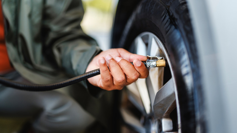 Man connecting a hose to a car tire