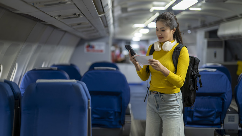 A woman looking at a smartphone on an airplane.