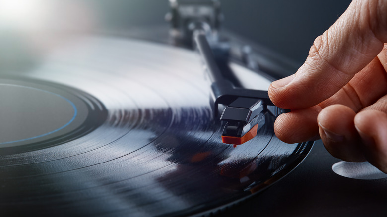 Close-up image of a hand placing a turntable stylus on a vinyl record.