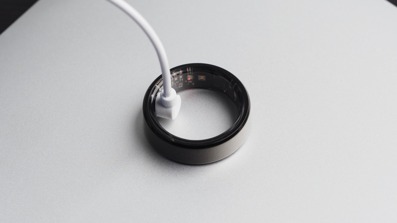 Smart ring connected to a charging cable and resting atop a counter.