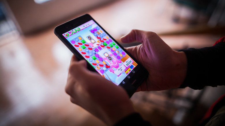Close up of a person's hands playing Candy Crush Saga on their smartphone