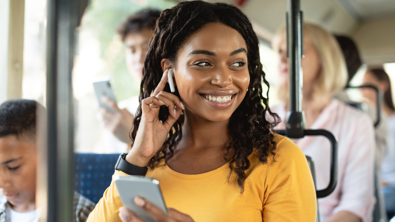 A smiling woman uses her smartphone on a bus
